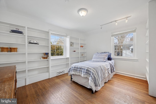 bedroom with visible vents, multiple windows, rail lighting, and wood-type flooring