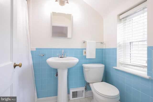 bathroom featuring visible vents, toilet, tile walls, and wainscoting