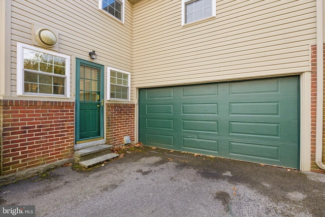 doorway to property with brick siding, driveway, and a garage