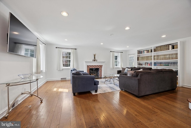 living room with visible vents, baseboards, recessed lighting, a fireplace, and wood-type flooring