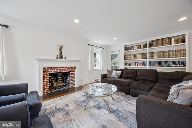 living room with recessed lighting, baseboards, a brick fireplace, and wood finished floors