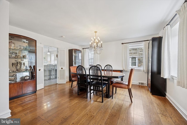 dining room featuring hardwood / wood-style flooring, a healthy amount of sunlight, visible vents, and arched walkways