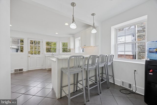 kitchen with light countertops, white cabinets, light tile patterned flooring, and visible vents