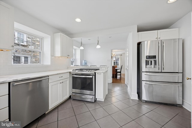 kitchen featuring tasteful backsplash, light tile patterned floors, appliances with stainless steel finishes, and white cabinetry