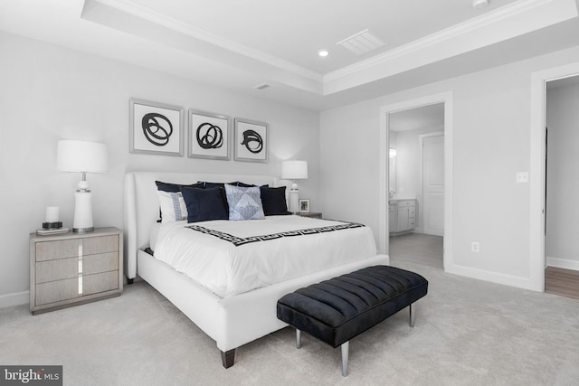 bedroom featuring ensuite bathroom, a raised ceiling, crown molding, and light carpet