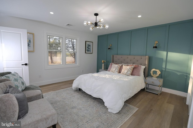 bedroom featuring wood-type flooring and an inviting chandelier