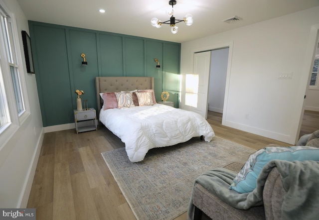 bedroom with light wood-type flooring, an inviting chandelier, and a closet