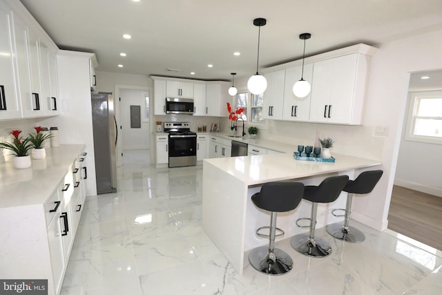 kitchen with stainless steel appliances, kitchen peninsula, white cabinets, decorative light fixtures, and sink