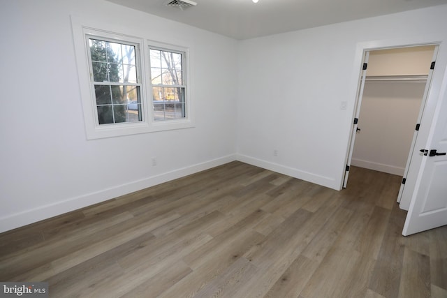 unfurnished bedroom featuring a walk in closet, a closet, and light hardwood / wood-style floors