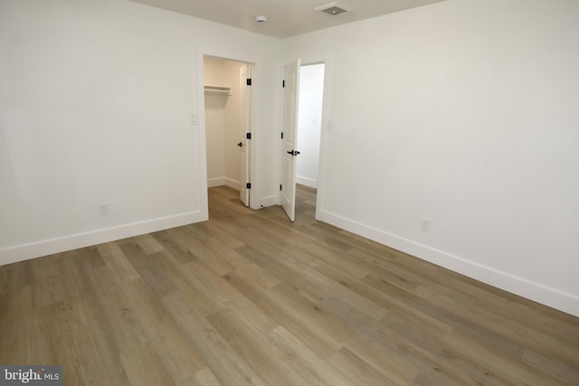 unfurnished bedroom with a closet, light wood-type flooring, and a spacious closet