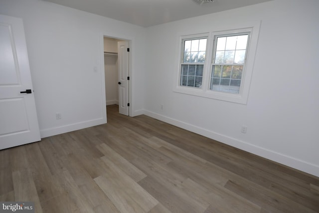 unfurnished bedroom with a walk in closet, a closet, and light hardwood / wood-style flooring