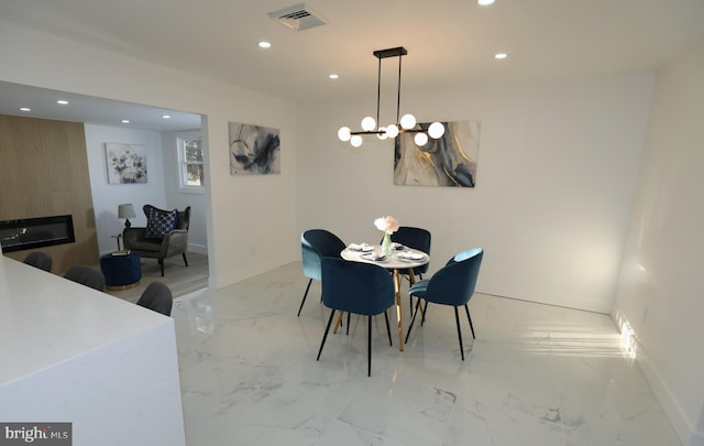 dining area featuring a chandelier and a large fireplace