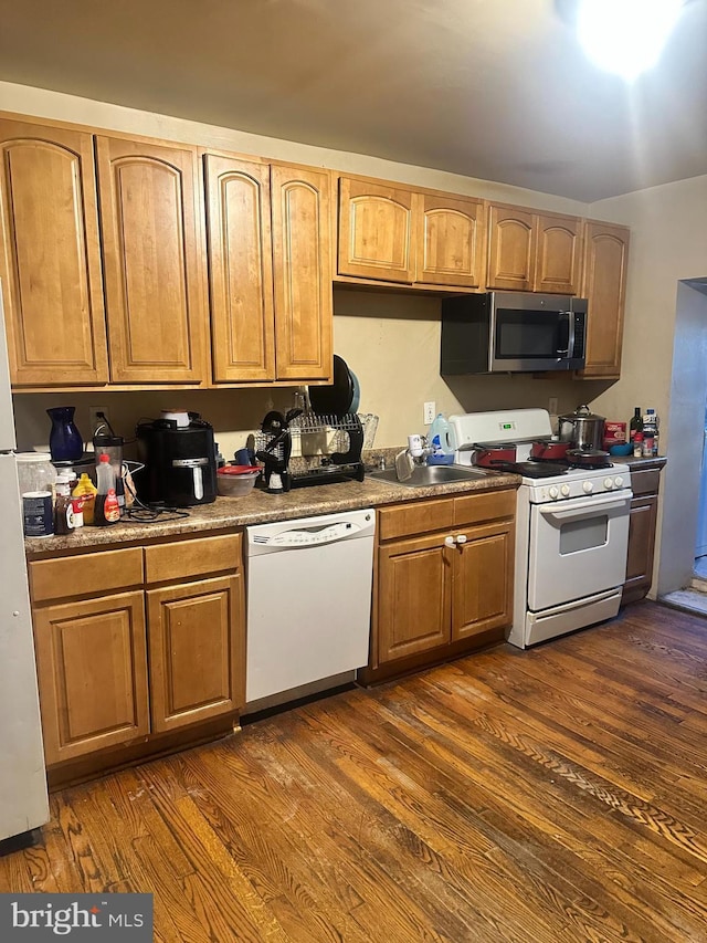 kitchen featuring white appliances, dark hardwood / wood-style flooring, and sink