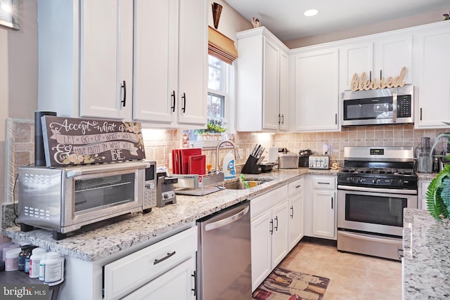 kitchen with tasteful backsplash, stainless steel appliances, sink, and white cabinets