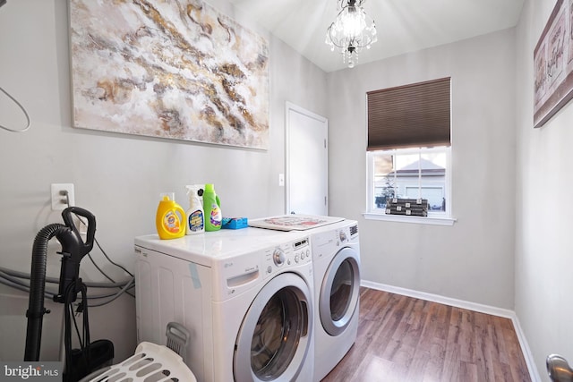 clothes washing area featuring separate washer and dryer, wood-type flooring, and a chandelier