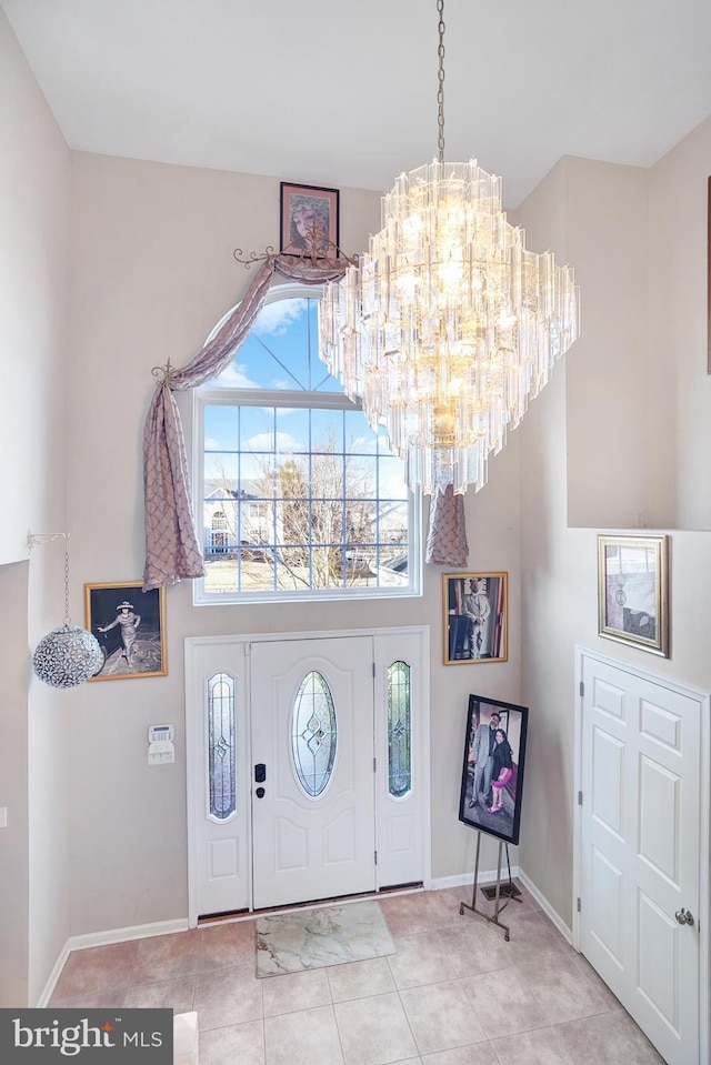 foyer with a high ceiling, light tile patterned flooring, and a chandelier