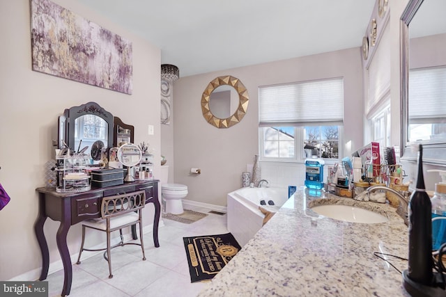 bathroom with tile patterned flooring, vanity, a relaxing tiled tub, and toilet