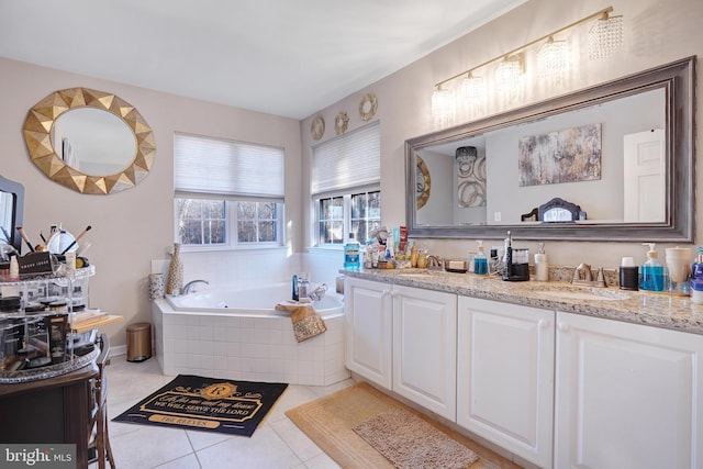 bathroom with tile patterned flooring, vanity, and tiled bath