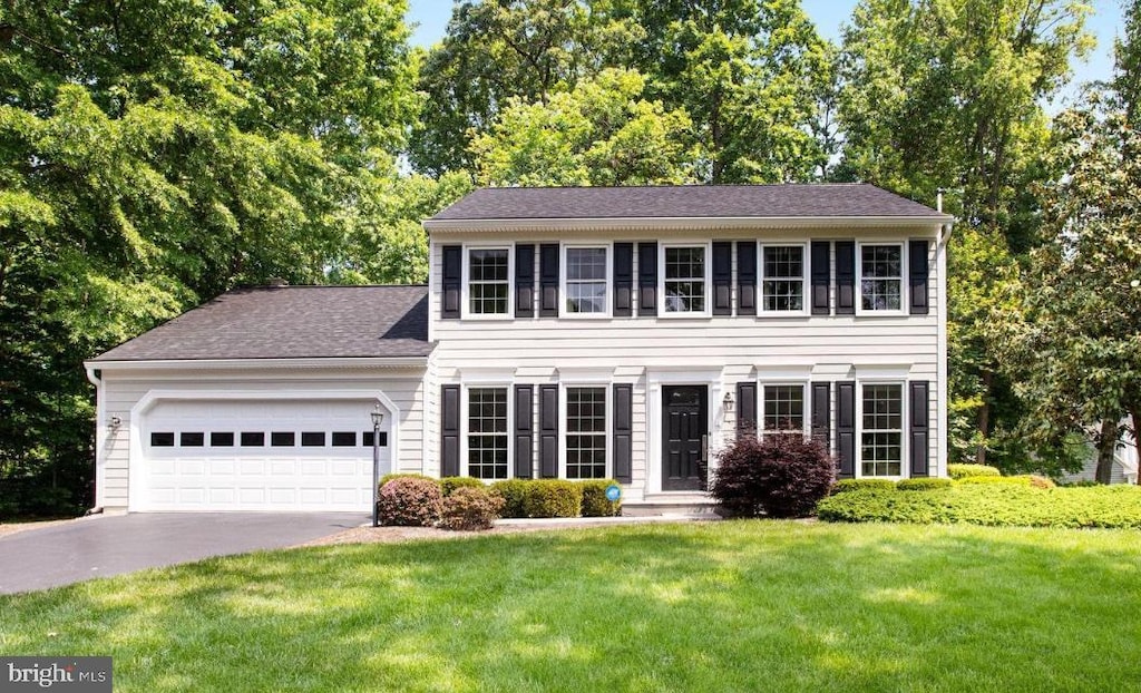 colonial inspired home with a garage and a front lawn