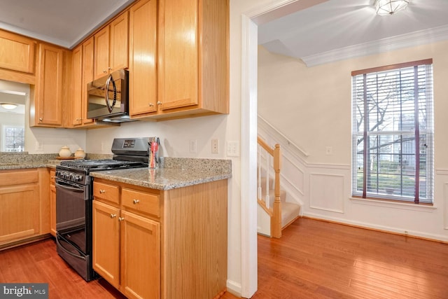 kitchen featuring light hardwood / wood-style flooring, black range with gas cooktop, plenty of natural light, light stone countertops, and ornamental molding