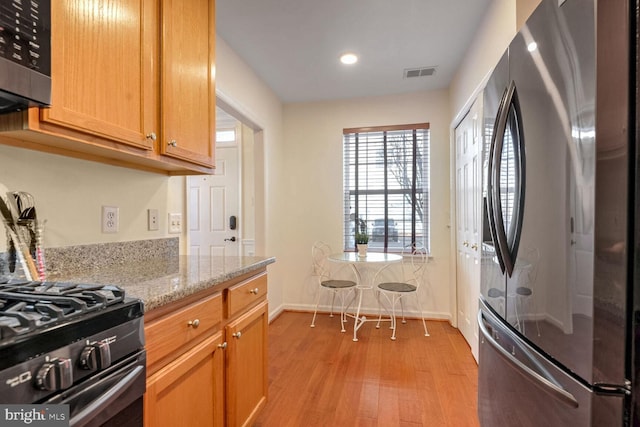 kitchen with light stone counters, stainless steel appliances, and light hardwood / wood-style floors