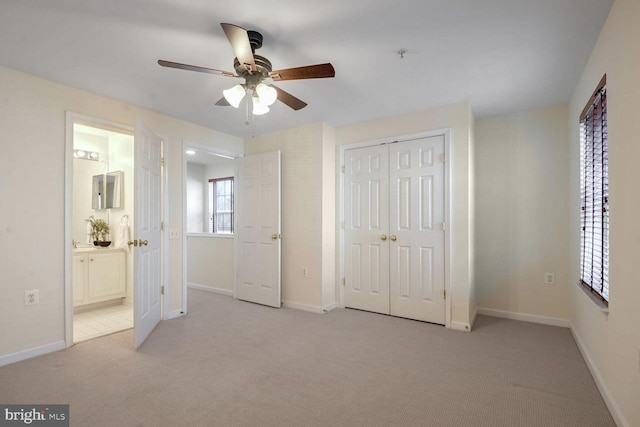 unfurnished bedroom with ceiling fan, a closet, ensuite bathroom, and light carpet