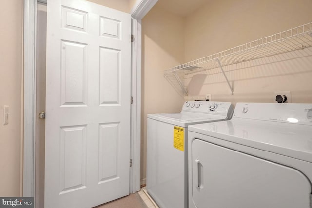 laundry area with separate washer and dryer and light tile patterned floors