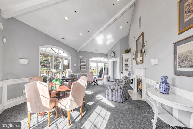 dining area featuring carpet floors, a fireplace, high vaulted ceiling, and beamed ceiling