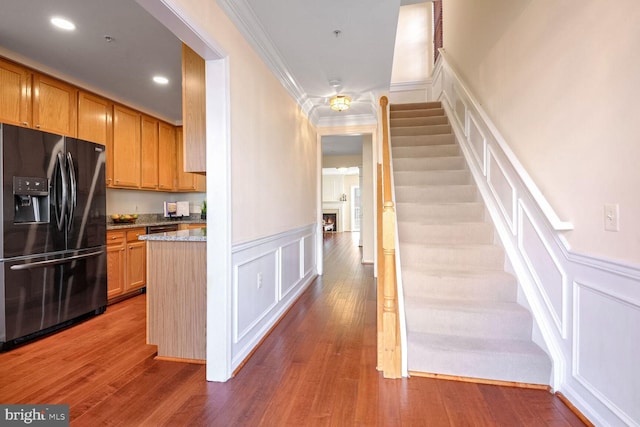 kitchen featuring crown molding, dark hardwood / wood-style floors, light stone counters, and black refrigerator with ice dispenser