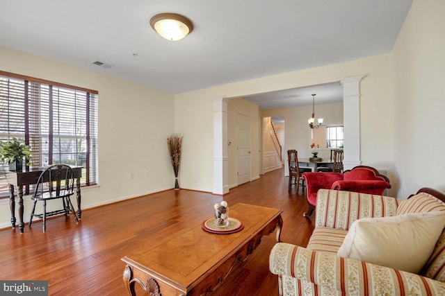 living room featuring an inviting chandelier, hardwood / wood-style flooring, and ornate columns