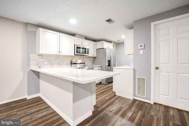 kitchen featuring a textured ceiling, white cabinets, stainless steel appliances, backsplash, and kitchen peninsula