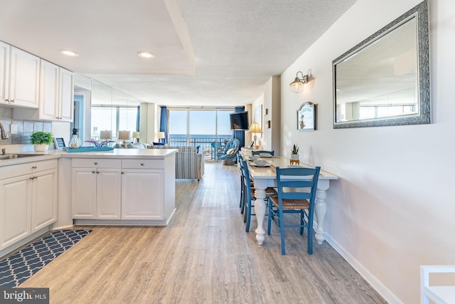 kitchen with white cabinetry, light wood-type flooring, a healthy amount of sunlight, and kitchen peninsula