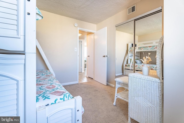 bedroom with light colored carpet, a closet, and a textured ceiling