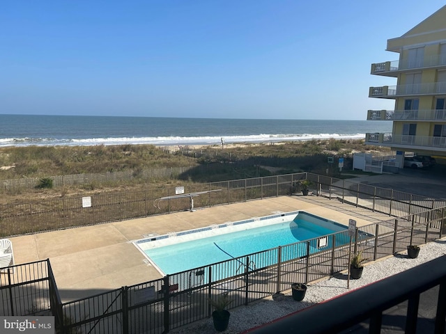 view of pool with a patio, a view of the beach, and a water view