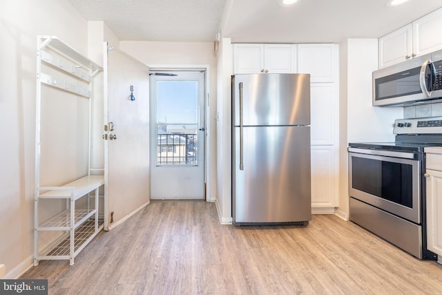 kitchen featuring stainless steel appliances, a textured ceiling, white cabinets, and light hardwood / wood-style flooring