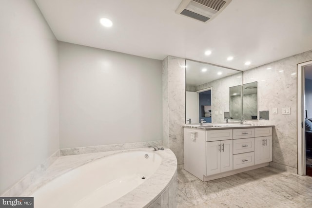 bathroom featuring a relaxing tiled tub and vanity