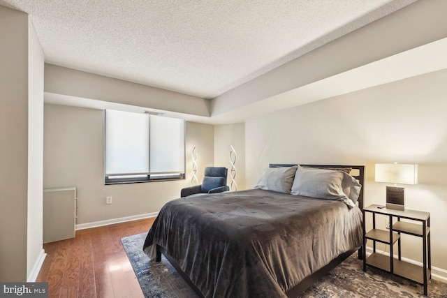 bedroom with dark hardwood / wood-style floors and a textured ceiling