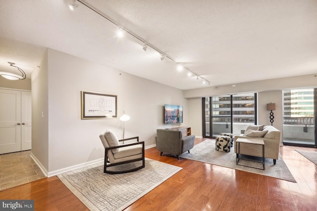 living room featuring hardwood / wood-style floors, rail lighting, and a textured ceiling