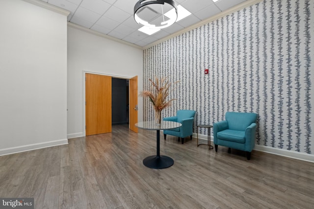 unfurnished room featuring crown molding, a towering ceiling, and hardwood / wood-style floors