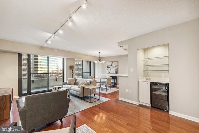 living room with wood-type flooring, bar area, beverage cooler, and a textured ceiling