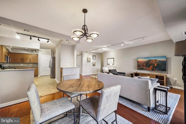 dining space with a textured ceiling, a notable chandelier, and light wood-type flooring