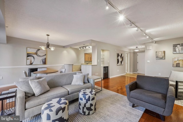 living room featuring track lighting, hardwood / wood-style floors, and a textured ceiling