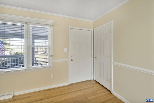 entryway featuring a textured ceiling, crown molding, and light hardwood / wood-style flooring