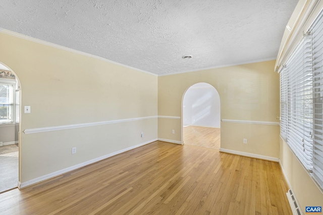 unfurnished room with a textured ceiling, crown molding, and light hardwood / wood-style flooring