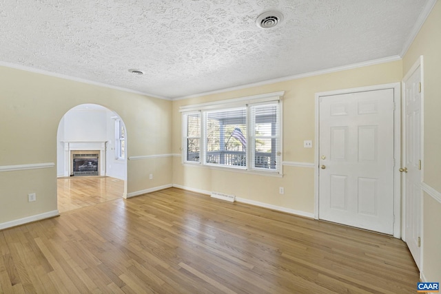 foyer entrance featuring a tile fireplace, a textured ceiling, ornamental molding, and hardwood / wood-style flooring