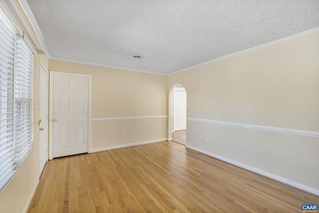 spare room featuring ornamental molding, light wood-type flooring, and a textured ceiling