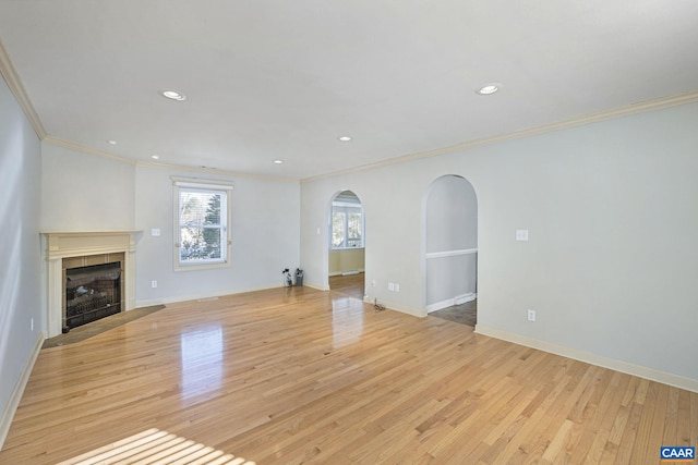 unfurnished living room with light wood-type flooring, crown molding, and a fireplace