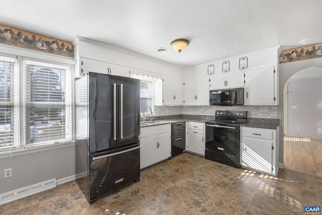 kitchen featuring black appliances, a healthy amount of sunlight, decorative backsplash, white cabinetry, and a baseboard radiator