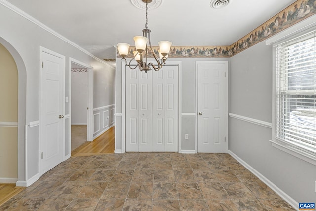 unfurnished dining area featuring an inviting chandelier and crown molding