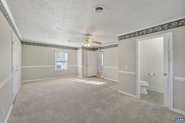 unfurnished bedroom featuring ceiling fan, light colored carpet, connected bathroom, and a textured ceiling